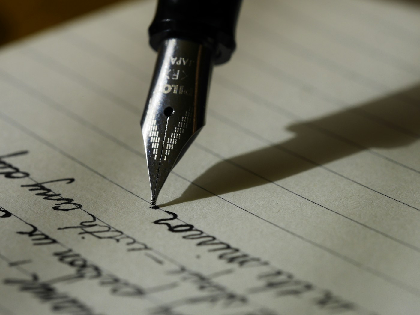A pen writing on an open notebook page